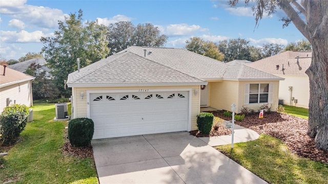 ranch-style house with cooling unit, a garage, and a front yard