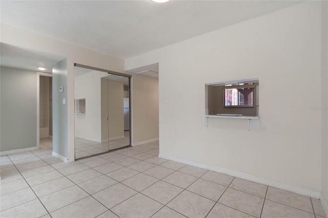 tiled empty room with a textured ceiling