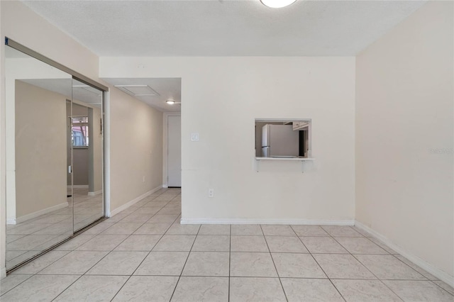 spare room featuring light tile patterned floors and a textured ceiling