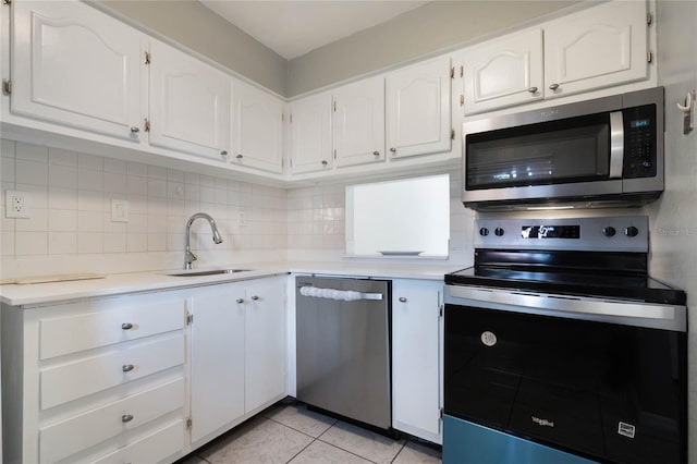 kitchen featuring sink, light tile patterned floors, white cabinetry, backsplash, and stainless steel appliances