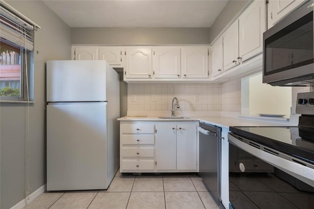 kitchen with appliances with stainless steel finishes, sink, white cabinets, backsplash, and light tile patterned floors