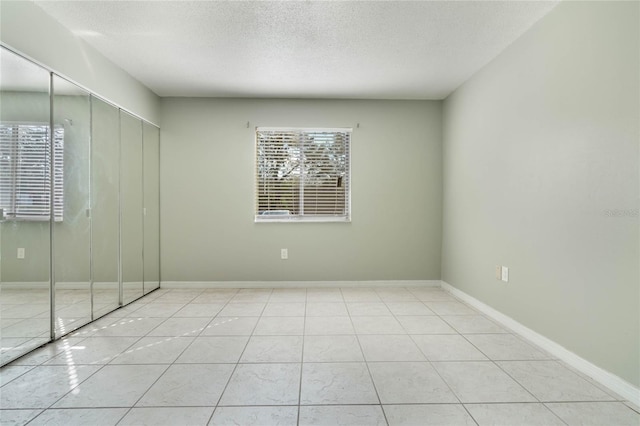 empty room with light tile patterned floors and a textured ceiling