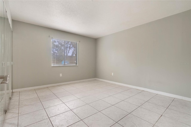 unfurnished room featuring light tile patterned flooring and a textured ceiling