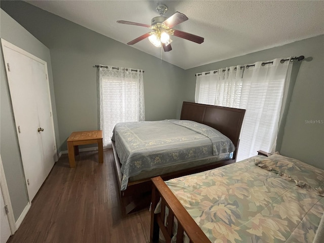 bedroom featuring multiple windows, dark hardwood / wood-style flooring, vaulted ceiling, and a textured ceiling