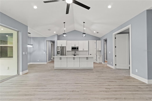 kitchen with an island with sink, sink, white cabinets, hanging light fixtures, and stainless steel appliances