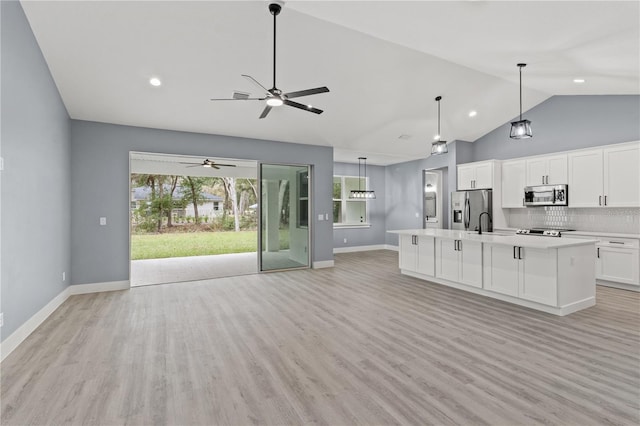 kitchen with white cabinetry, a center island with sink, light wood-type flooring, pendant lighting, and stainless steel appliances