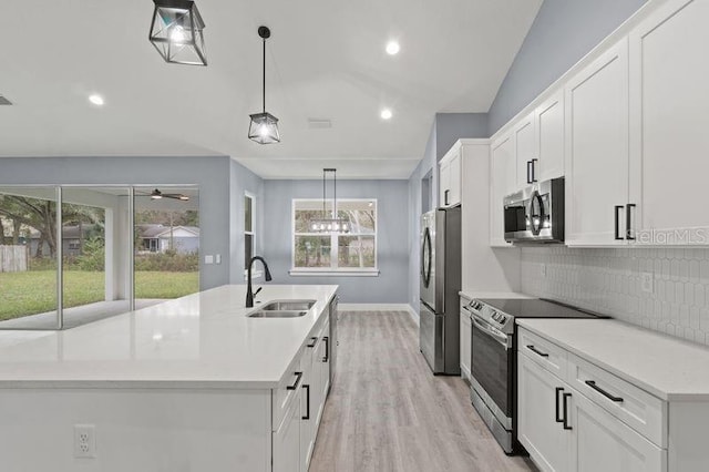 kitchen with sink, appliances with stainless steel finishes, white cabinetry, backsplash, and hanging light fixtures