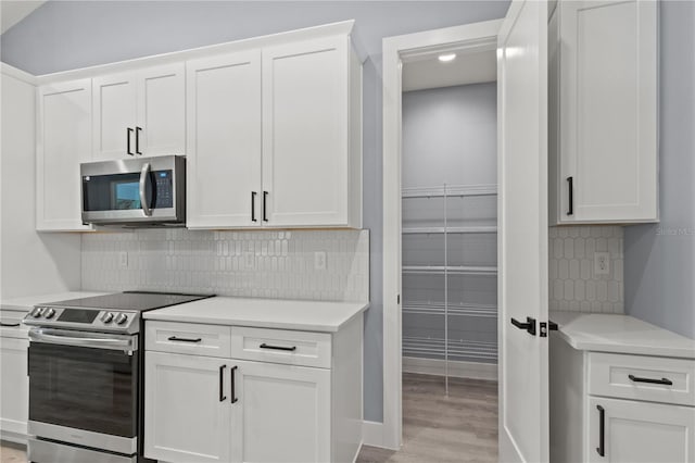 kitchen with tasteful backsplash, white cabinetry, and appliances with stainless steel finishes