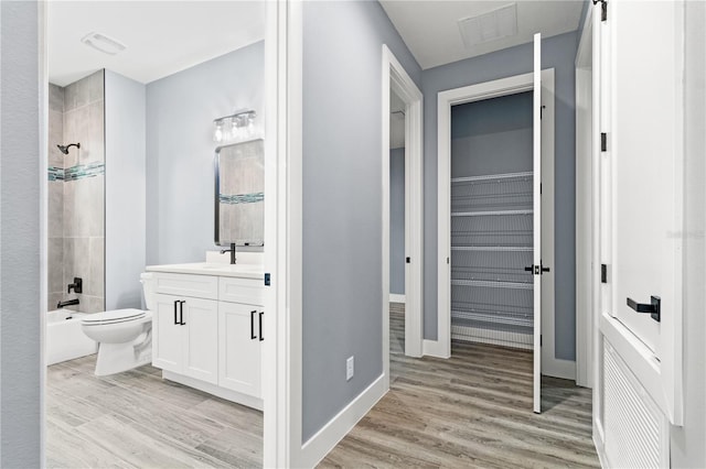 full bathroom featuring tiled shower / bath, vanity, toilet, and hardwood / wood-style floors