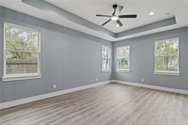 unfurnished room featuring ceiling fan, a raised ceiling, and light hardwood / wood-style flooring