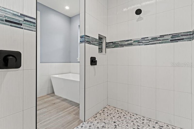 bathroom with independent shower and bath, wood-type flooring, and tile walls