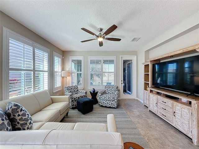 living room with a textured ceiling and ceiling fan