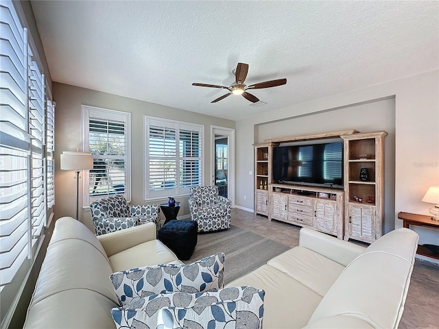 living room featuring ceiling fan and a textured ceiling