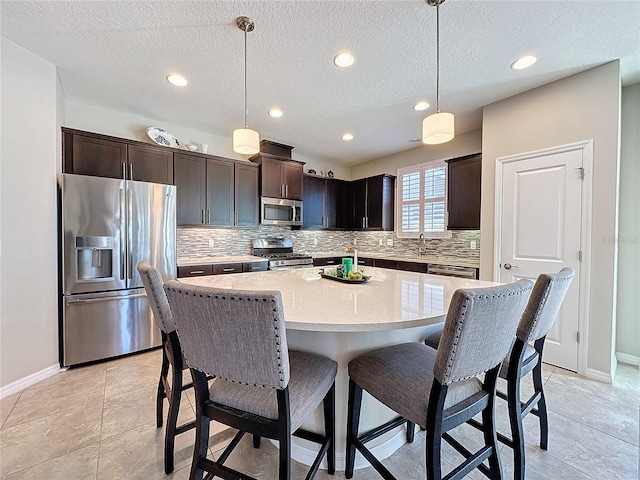 kitchen featuring dark brown cabinets, a center island, appliances with stainless steel finishes, and pendant lighting