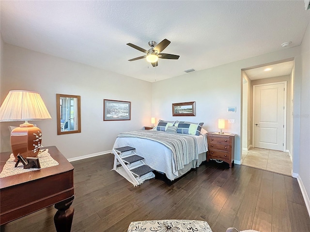 bedroom with ceiling fan, dark wood-type flooring, and a textured ceiling