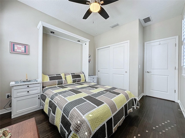 bedroom with a textured ceiling, a closet, dark hardwood / wood-style floors, and ceiling fan