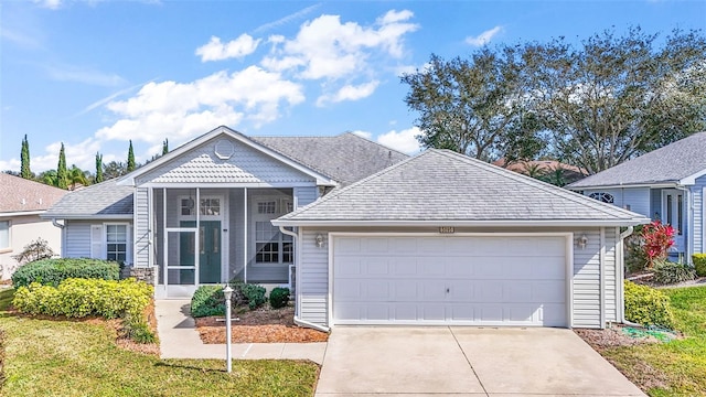 view of front of property featuring a garage, a sunroom, and a front lawn