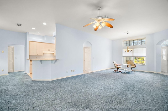 unfurnished living room featuring ceiling fan with notable chandelier and light colored carpet