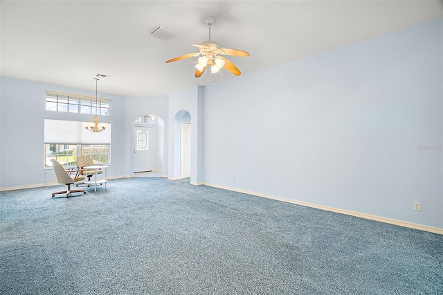 empty room with ceiling fan with notable chandelier and carpet floors