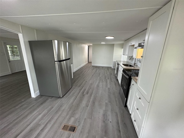 kitchen featuring sink, white cabinetry, stainless steel refrigerator, electric stove, and light hardwood / wood-style floors