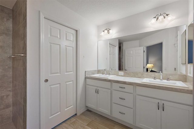 bathroom featuring hardwood / wood-style flooring, tiled shower, vanity, and a textured ceiling