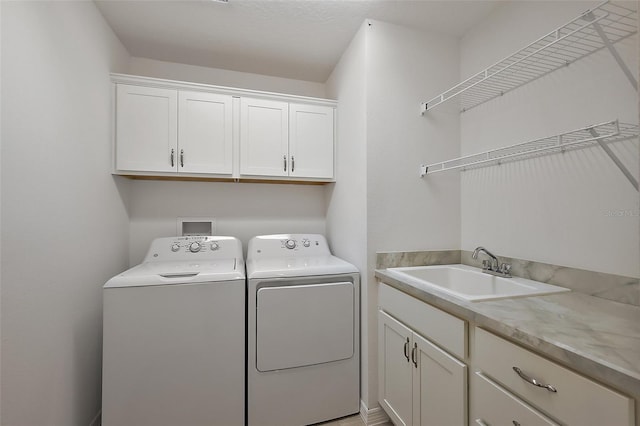 clothes washing area with cabinets, sink, and washer and dryer