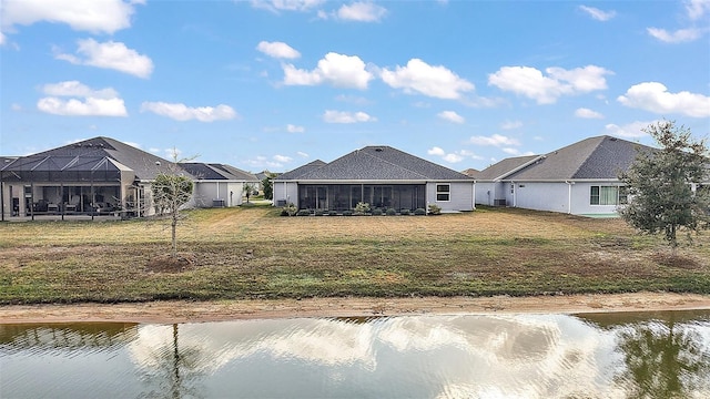 back of property featuring a water view, a sunroom, glass enclosure, and a lawn