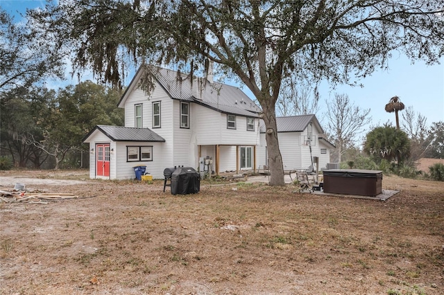 rear view of house featuring an outbuilding and a hot tub