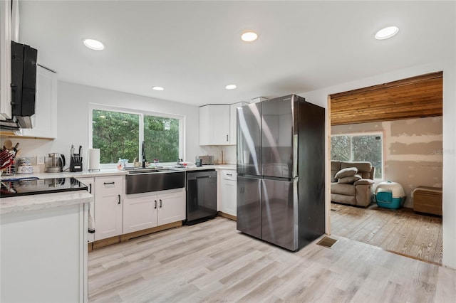 kitchen with stainless steel appliances, white cabinetry, sink, and a wealth of natural light