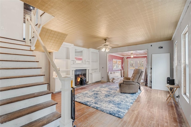 living room with a tile fireplace, ceiling fan, and light hardwood / wood-style flooring