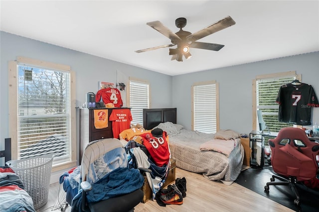 bedroom featuring multiple windows, hardwood / wood-style floors, and ceiling fan