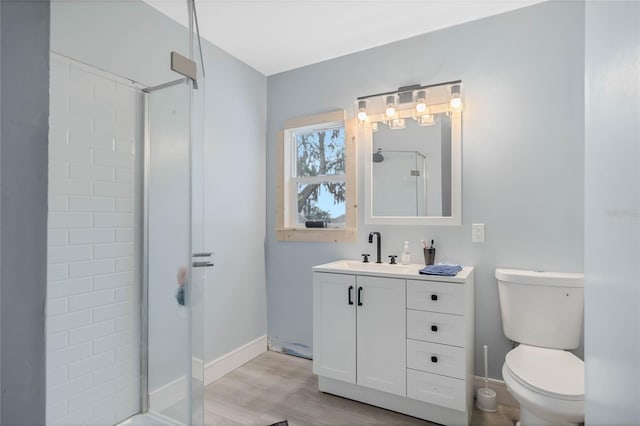 bathroom featuring vanity, wood-type flooring, toilet, and walk in shower