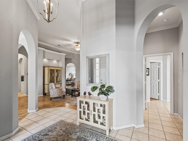 corridor featuring light tile patterned flooring, crown molding, and a high ceiling