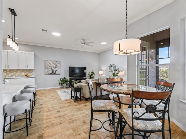 dining space with crown molding, ceiling fan, and light wood-type flooring