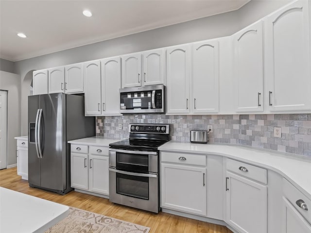 kitchen with backsplash, light hardwood / wood-style floors, white cabinets, and appliances with stainless steel finishes