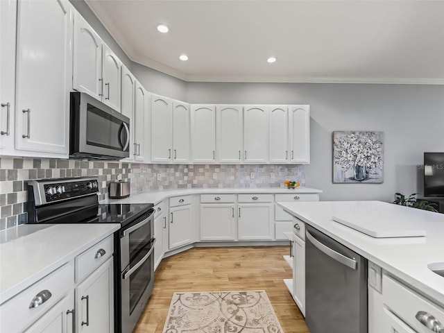 kitchen with tasteful backsplash, appliances with stainless steel finishes, white cabinets, and light wood-type flooring