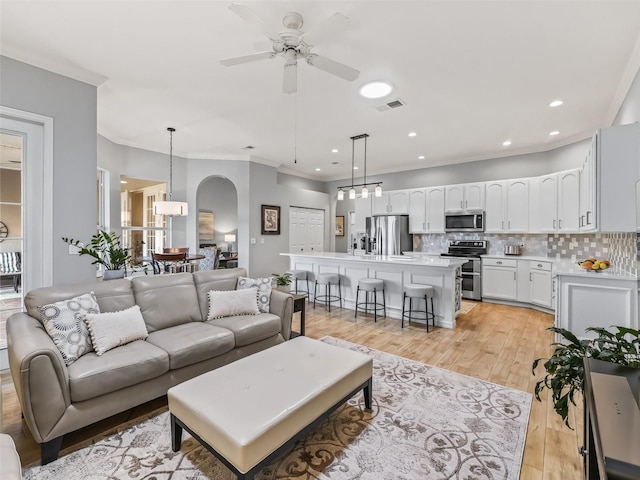 living room with light hardwood / wood-style flooring, ornamental molding, and ceiling fan