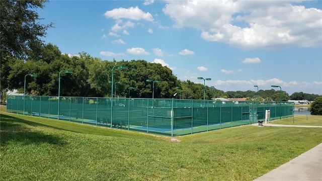 view of tennis court featuring a yard