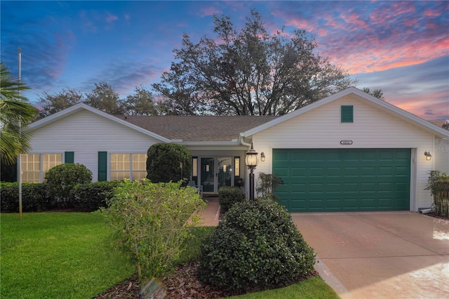 single story home with a lawn, a shingled roof, driveway, and an attached garage