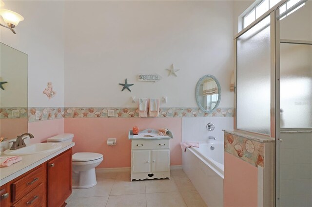 bathroom with tile patterned floors, a wainscoted wall, toilet, a bath, and vanity