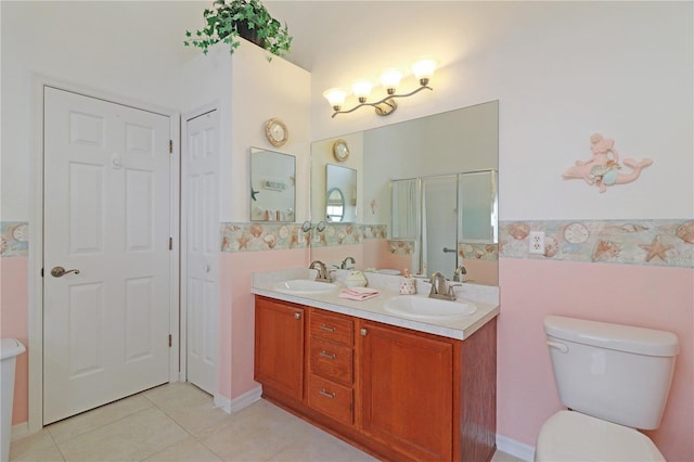 bathroom with tile patterned floors, toilet, double vanity, and a sink