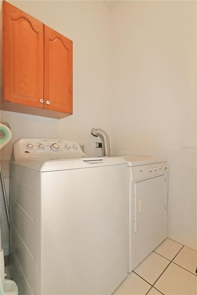 washroom featuring cabinet space, light tile patterned flooring, and washing machine and clothes dryer
