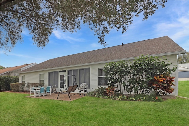 rear view of house featuring a patio, a yard, and roof with shingles