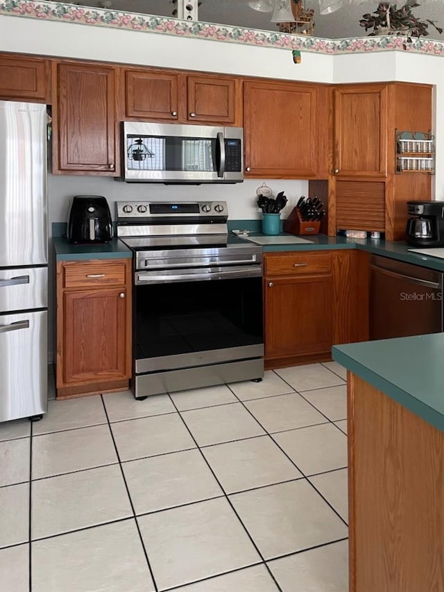 kitchen featuring light tile patterned flooring, brown cabinets, and stainless steel appliances