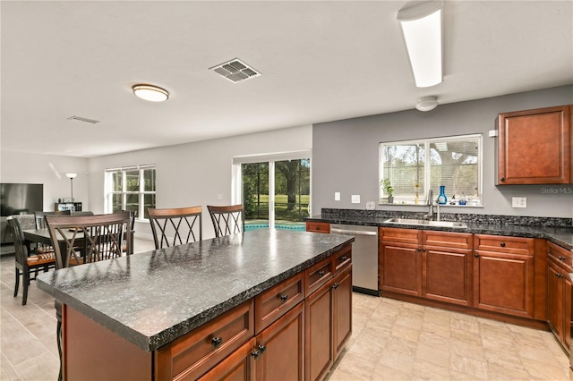 kitchen with stainless steel dishwasher, sink, and a kitchen island