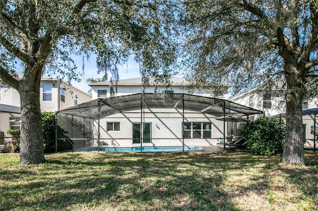 back of house featuring glass enclosure and a lawn