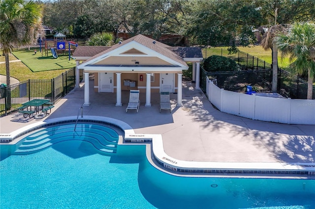 view of swimming pool with a patio area, a playground, and a lawn