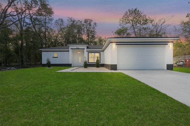 mid-century home with concrete driveway, a lawn, a garage, and stucco siding