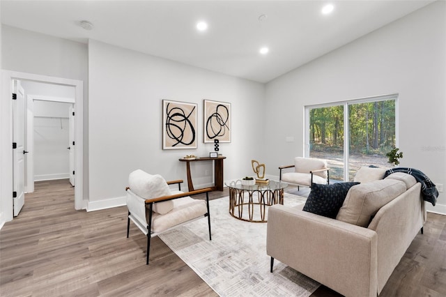 living room with lofted ceiling, recessed lighting, light wood-style floors, and baseboards