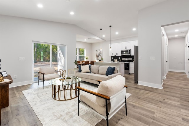 living room with recessed lighting, lofted ceiling, and light wood-style flooring